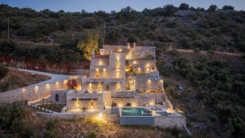 Una villa de piedra con varias habitaciones, piscina y una entrada sinuosa.