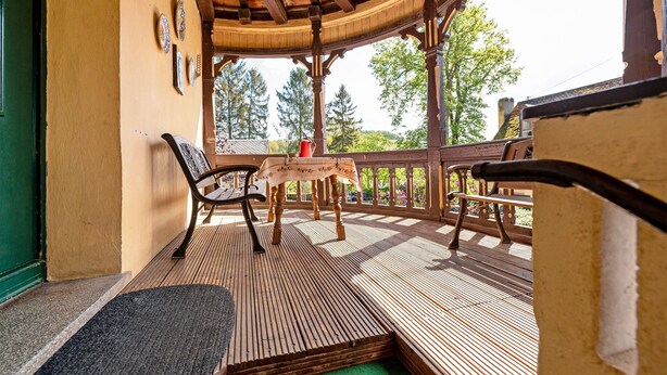 A covered outdoor seating area with a table and chairs, a wooden deck, and a view of trees. - Apartment 'Kavaliershäuschen' with Mountain View, Shared Garden and Wi-Fi (Maring-Noviand)