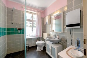 Une salle de bain équipée d’une douche, de toilettes, d’un lavabo et d’un miroir.