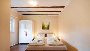 A double bed with a wooden frame, a white wardrobe, and a painting on the wall. - Apartment 'Kavaliershäuschen' with Mountain View, Shared Garden and Wi-Fi (Maring-Noviand)