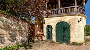 A building with a stone wall, a wooden balcony, and a green door. - Apartment 'Kavaliershäuschen' with Mountain View, Shared Garden and Wi-Fi (Maring-Noviand)