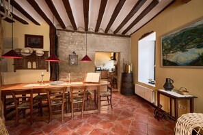 Un coin repas rustique avec une table en bois, des chaises et un mur en pierre.