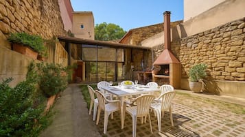 Un patio con una mesa y sillas, un muro de piedra y una chimenea.