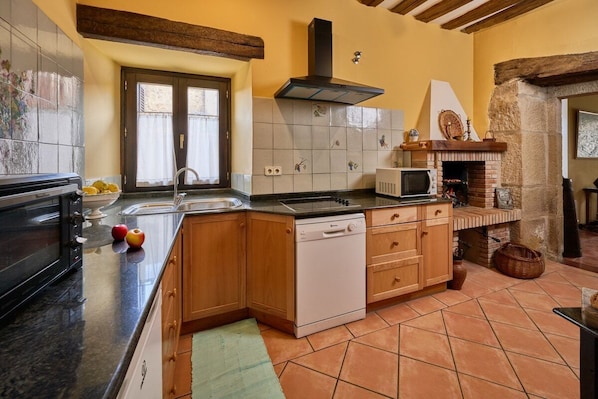 A kitchen with wooden cabinets, a dishwasher, a microwave, and a brick oven.