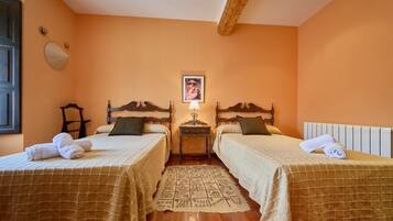 A room with two beds, a nightstand, a lamp, and a rug.