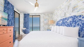 Un dormitorio con una cama grande, un tocador, una lámpara y vista al océano.