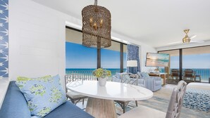 Une pièce moderne avec une table ronde, un canapé bleu à motifs et une vue sur l’océan.