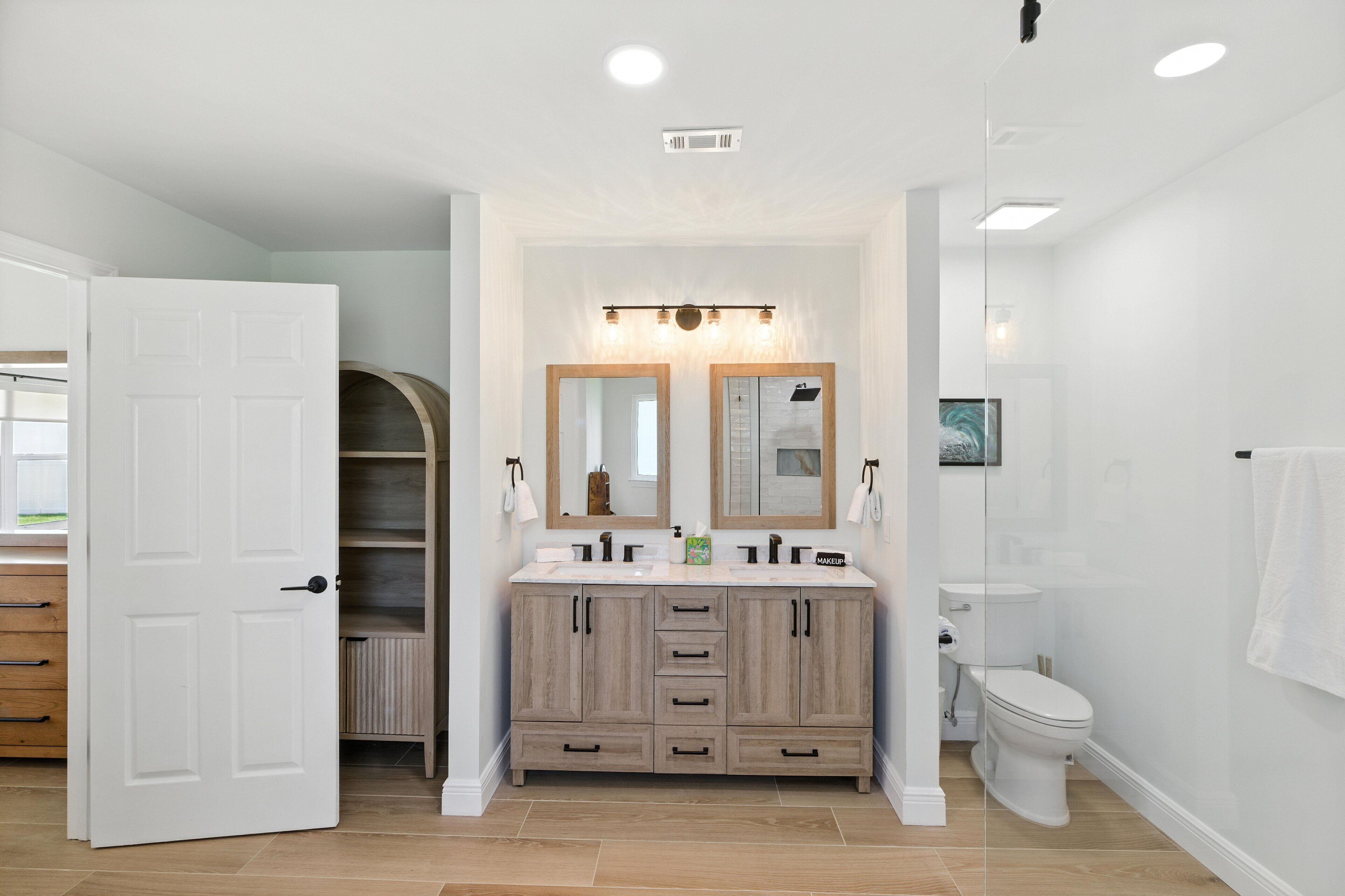 A modern bathroom with a double vanity, a toilet, and a shower.