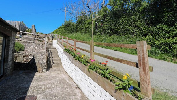 Un escalier en pierre menant à une clôture en bois ornée de fleurs aux couleurs vives.