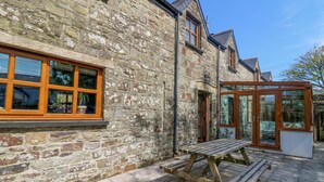 Un bâtiment en pierre avec un banc en bois et une porte vitrée donnant sur un patio.