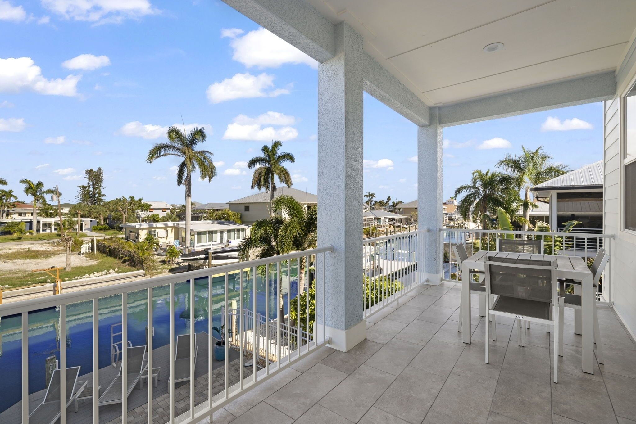 A balcony with a pool, white railings, and a table with chairs.