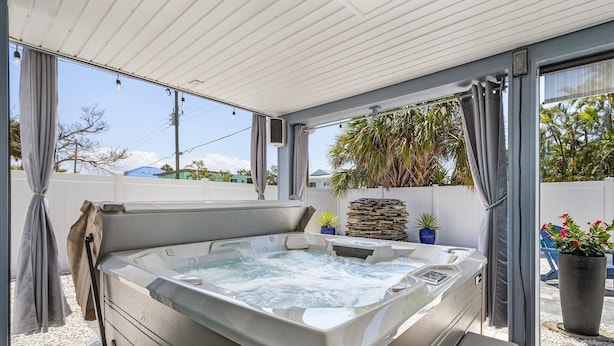A hot tub in a covered outdoor area with a view of the sky and surrounding vegetation. - 130 Tiki Tides: 2br W/ Outdoor Tiki Bar! 2 Bedroom Home (Fort Myers Beach)