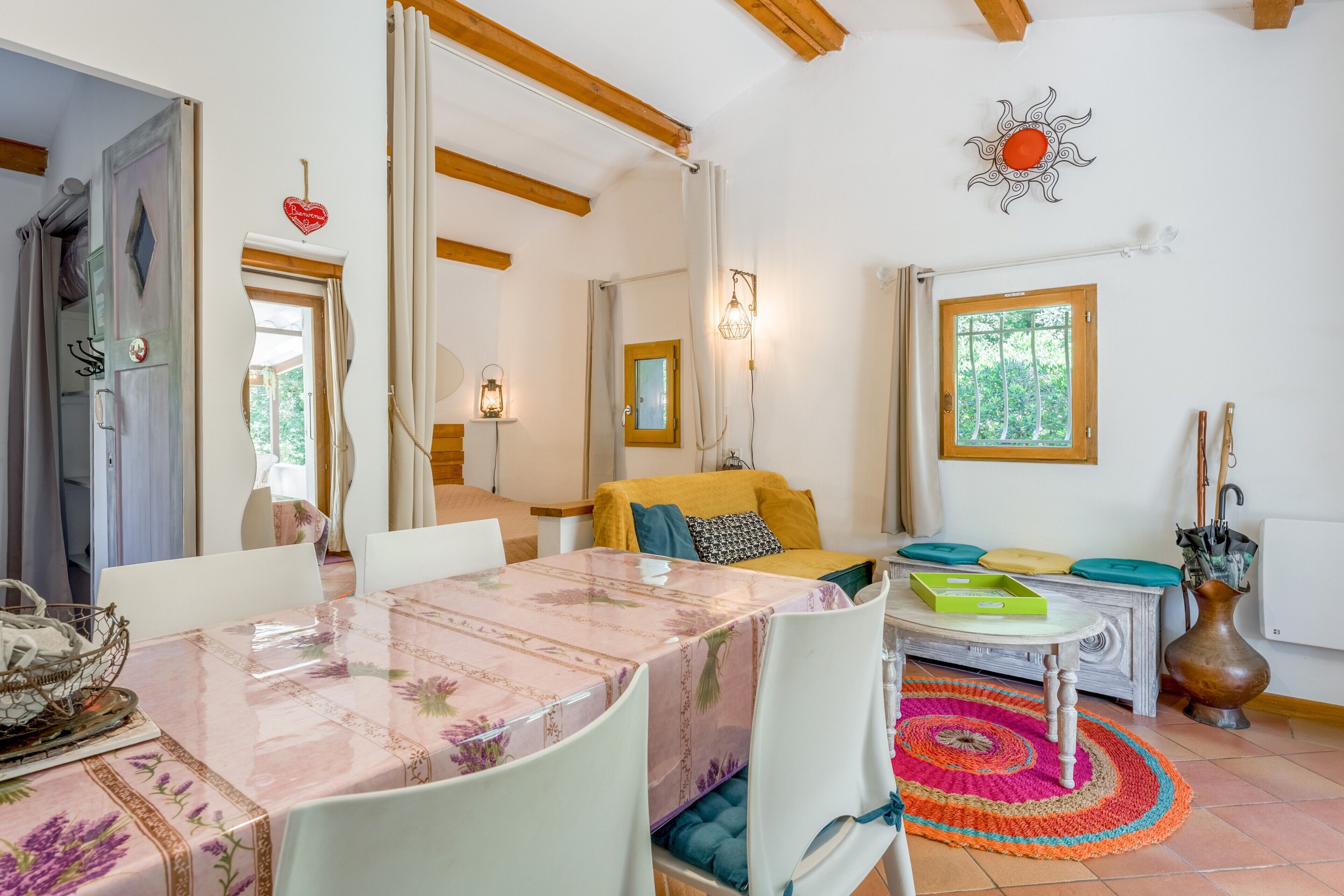 A cozy living room with a dining table, chairs, a sofa, and a window with a view.