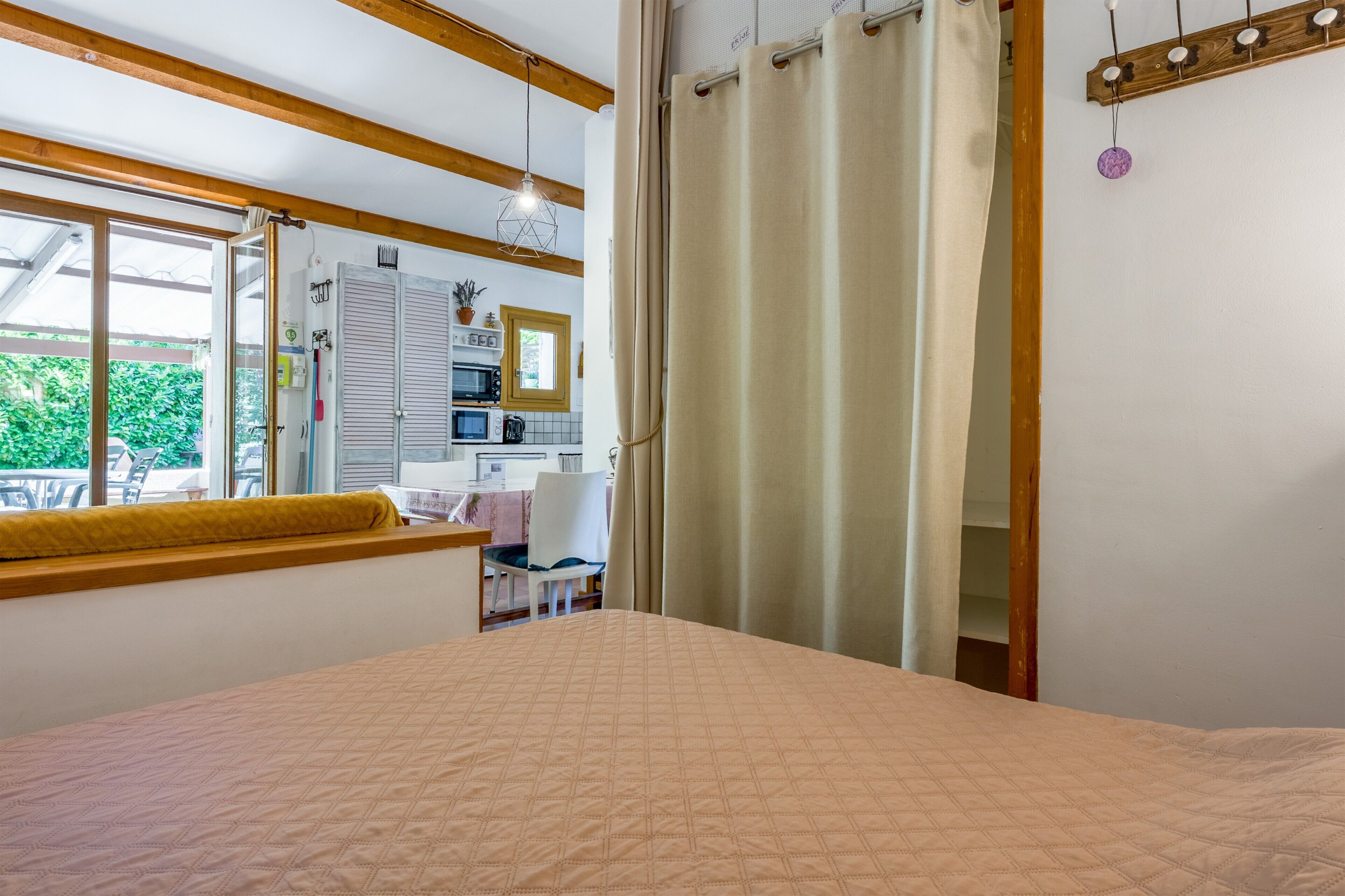 A bedroom with a bed, a window, a desk, and a kitchenette.