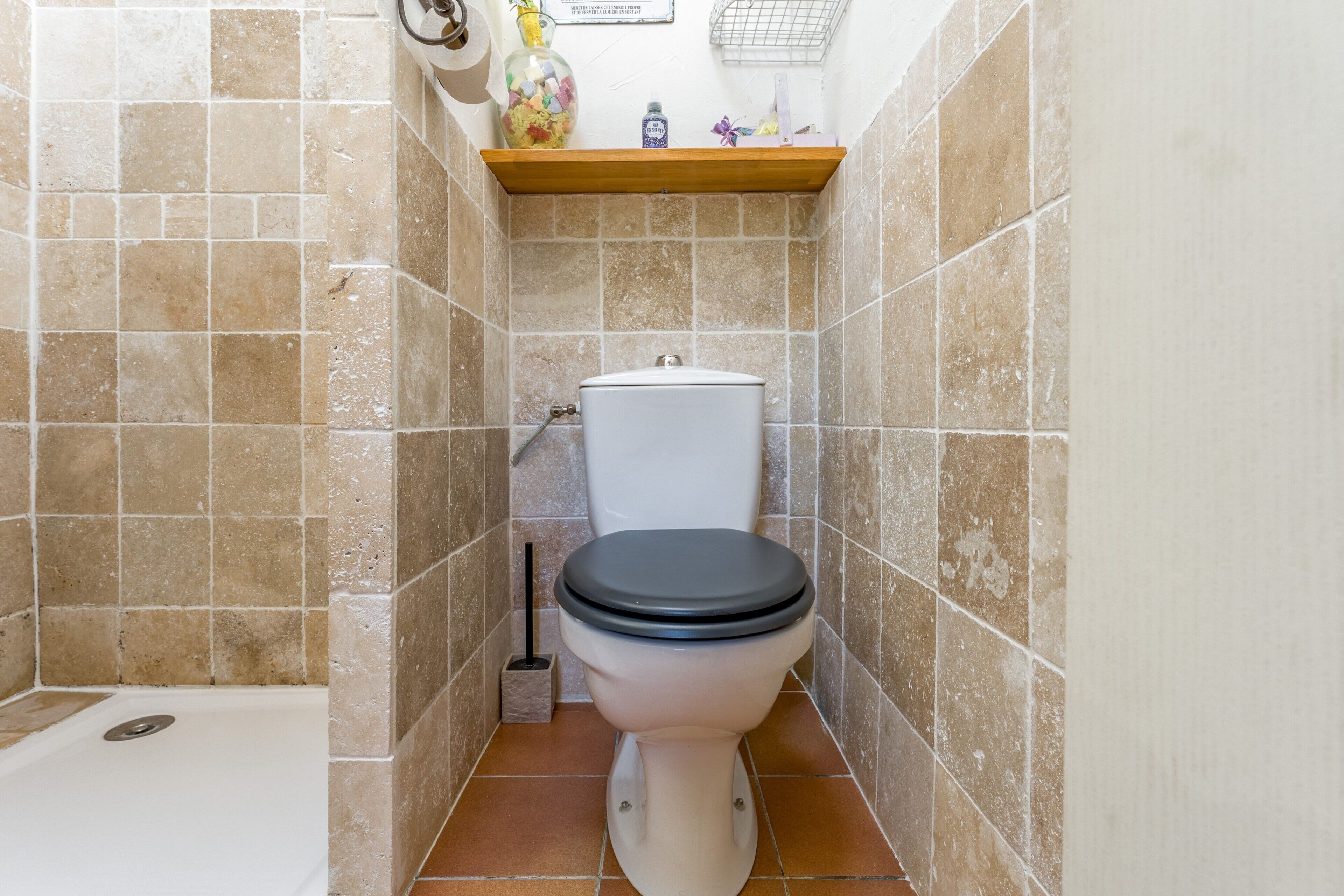 Ein Badezimmer mit Toilette, einer Badewanne und einem Ablagefach für Pflegeprodukte.
