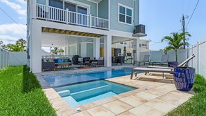 A two-story house with a backyard pool, outdoor seating, and a covered patio area.