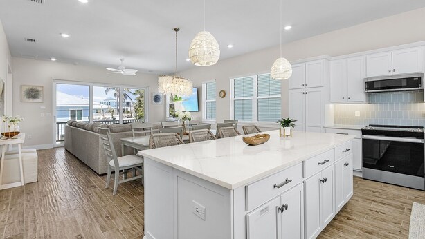 A modern kitchen with white cabinetry, a large island, and a dining area with wicker chairs.