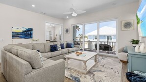 A spacious living room with a sectional sofa, a coffee table, and a view of the outdoors through large sliding glass doors.