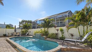 A swimming pool with a tiled edge, surrounded by a brick patio, and adjacent to a building with a balcony. - 241 Oasis Pearl: 3br Pool Home! 3 Bedroom Home (Fort Myers Beach)