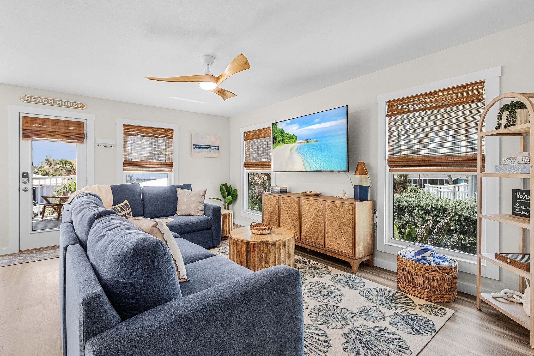A modern living room with a large sofa, a wooden cabinet, a TV, and a ceiling fan.