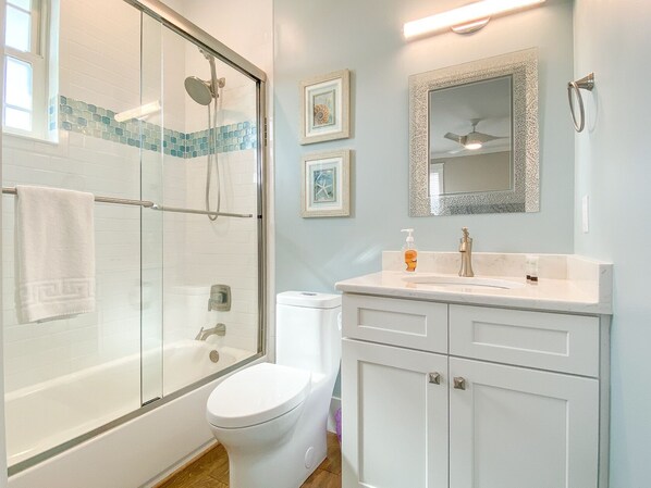 A bathroom with a glass-enclosed shower, a white toilet, and a vanity with a mirror.