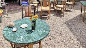 An outdoor seating area with round tables and chairs, a sign for 'Ecole', and a building with a timber-framed facade. - Chez Jacques-Louis (Cosne-Cours-sur-Loire)