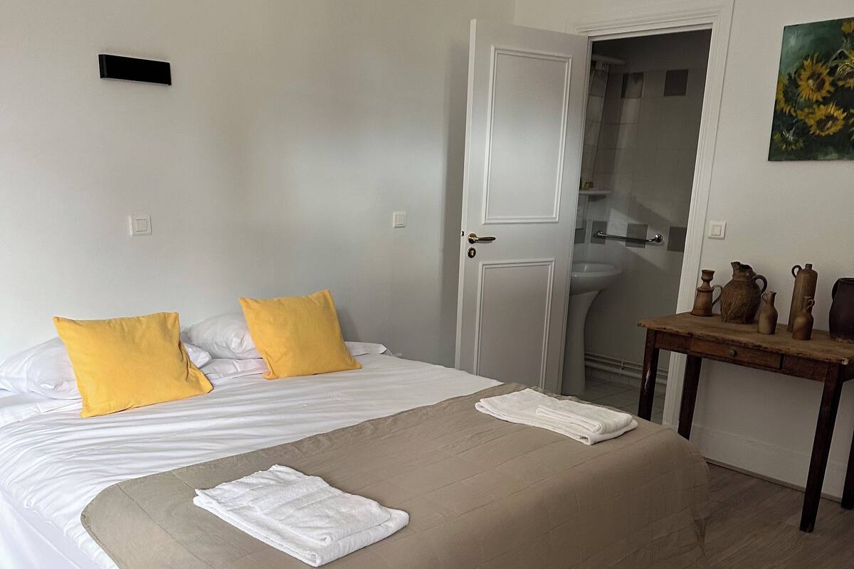A hotel room with a bed, a wooden table, and a door leading to a bathroom.