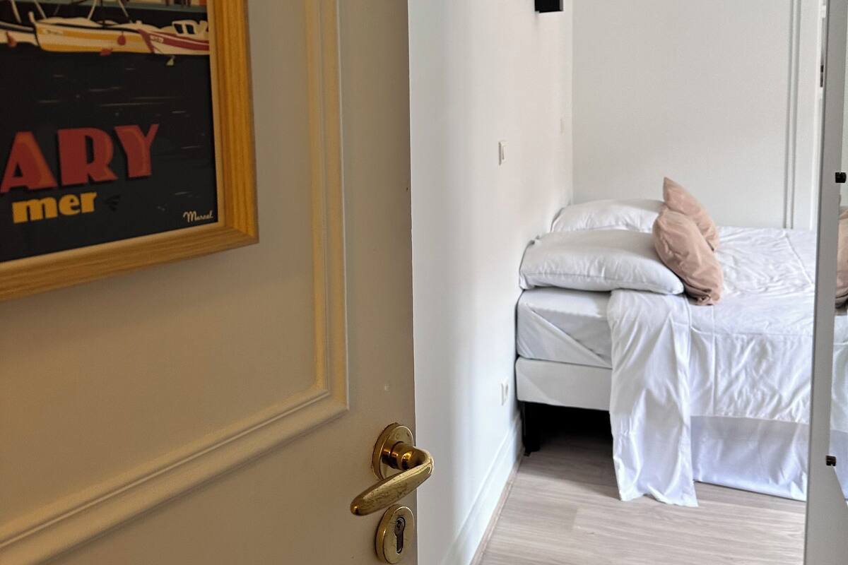 A hotel room with a bed, pillows, and a door with a brass handle.