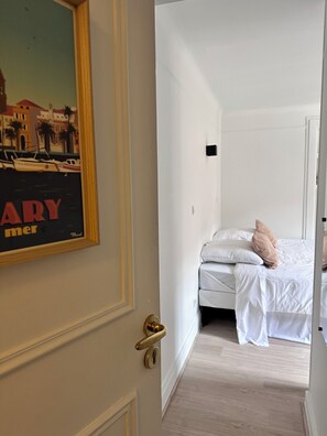 Una camera d'albergo con un letto, cuscini e una porta con maniglia in ottone.
