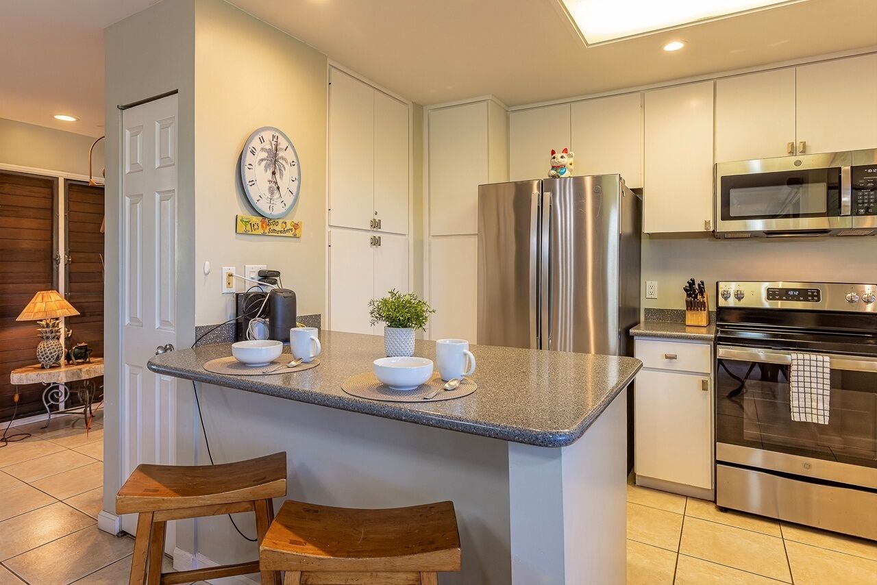 A modern kitchen with a central island, stainless steel appliances, and a clock on the wall.