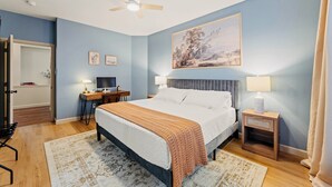 A bedroom with a bed, bedside tables, a desk, a chair, and a ceiling fan.