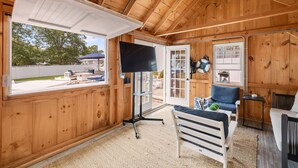 A wooden cabin interior with a TV, seating area, and a view of the outdoors.
