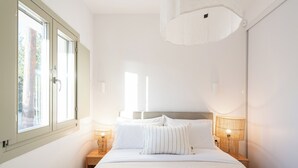 Une chambre à coucher avec un grand lit, deux lampes de chevet et une fenêtre donnant sur des arbres.