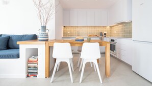 Eine moderne Küche mit weißen Schränken, einem Holztisch und zwei weißen Stühlen.