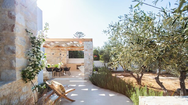 An outdoor patio area with stone walls, a pergola, and a seating arrangement.