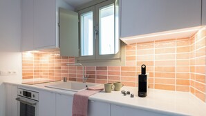 A modern kitchen with white cabinets, a double oven, a sink, and a window above the countertop.