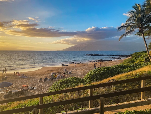 A beach with people, umbrellas, and a wooden fence.