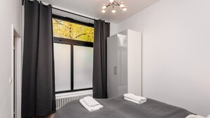 A modern bedroom with a bed, a wardrobe, and a window with curtains.