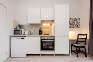 Une cuisine compacte équipée d’un lave-vaisselle, d’un four à micro-ondes, d’une cuisinière et d’un coin repas avec une chaise.