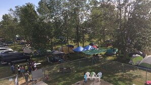 Un espacio de camping con tiendas de campaña, piscina y sillas de jardín.