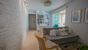 Una sala de estar moderna con un sofá, una mesa de comedor con sillas, una zona de cocina y un espejo grande.