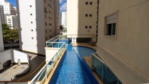 Una piscina en un edificio residencial con varios pisos y balcones.