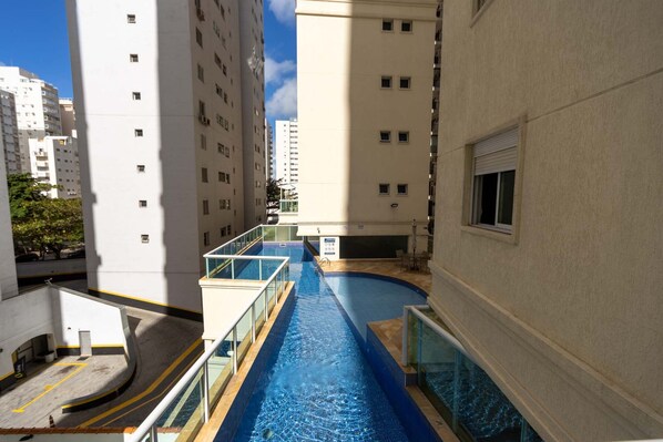 A swimming pool in a residential building with multiple floors and balconies.