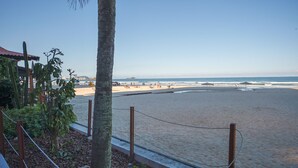 Una playa con una palmera, una valla de madera y cielo despejado.