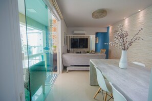A modern hotel room with a bed, a desk, and a large window.