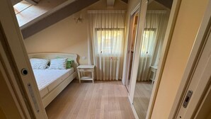 A bedroom with a bed, a small table, and a window with curtains. - Duplex with pool, terrace and 2 bedroom (Lenno)