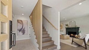 A modern interior with a staircase, a fireplace, and a living area.