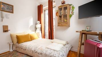 A bedroom with a bed, a wooden cabinet, a television, and a radiator.