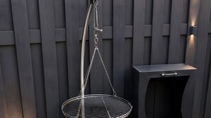 Un barbecue doté d’un couvercle rabattable, d’une table d’appoint et d’une terrasse dallée de pierres.