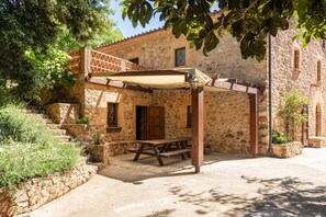 A stone building with a wooden bench and a pergola. - Can Pla - Disconnect to Connect (Sant Hilari Sacalm)